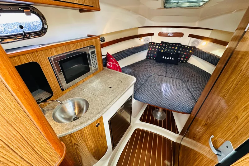 Slide: The Image of 2007 Pursuit OS 285 Offshore cabin with kitchenette, sink, and cozy sleeping area. - 25