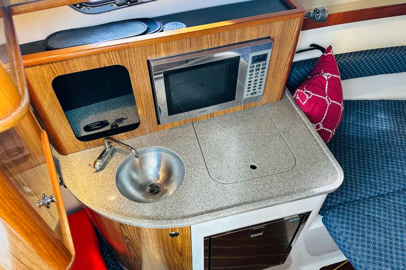 Slide: The Image of Compact galley in 2007 Pursuit OS 285 Offshore boat with sink, microwave, and seating. - 27