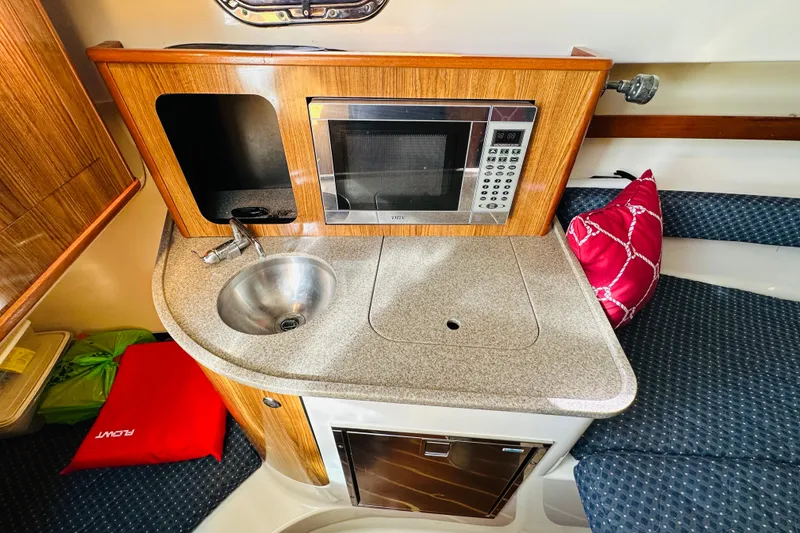 Slide: The Image of 2007 Pursuit OS 285 Offshore boat interior with kitchenette, sink, and microwave. - 28