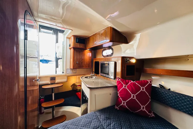 Slide: The Image of 2007 Pursuit OS 285 Offshore cabin interior with kitchenette, seating, and wooden accents. - 30