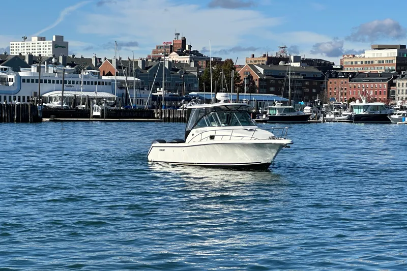 Slide: The Image of 2007 Pursuit OS 285 Offshore boat on water with cityscape background. - 37