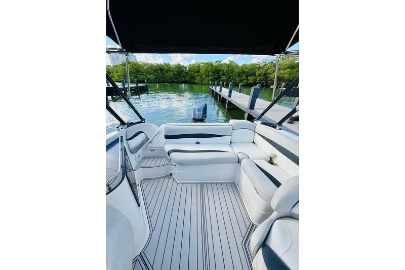 Slide: The Image of 2015 Starcraft Crossover 250 SCX OB boat interior with seating, docked by lush greenery. - 16