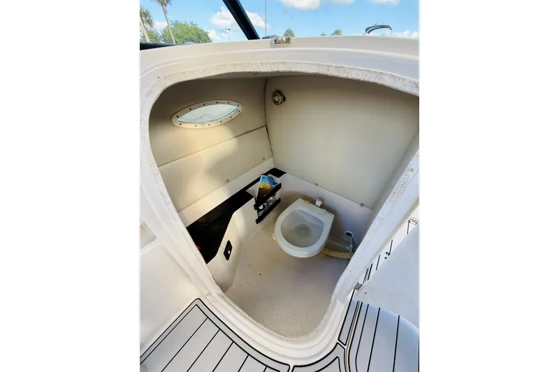 Slide: The Image of 2015 Starcraft Crossover 250 SCX OB boat interior with compact toilet and porthole. - 24