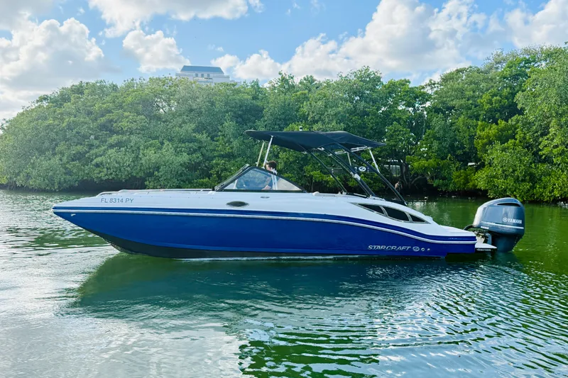 Slide: The Image of 2015 Starcraft Crossover 250 SCX OB boat on calm water with lush greenery background. - 37