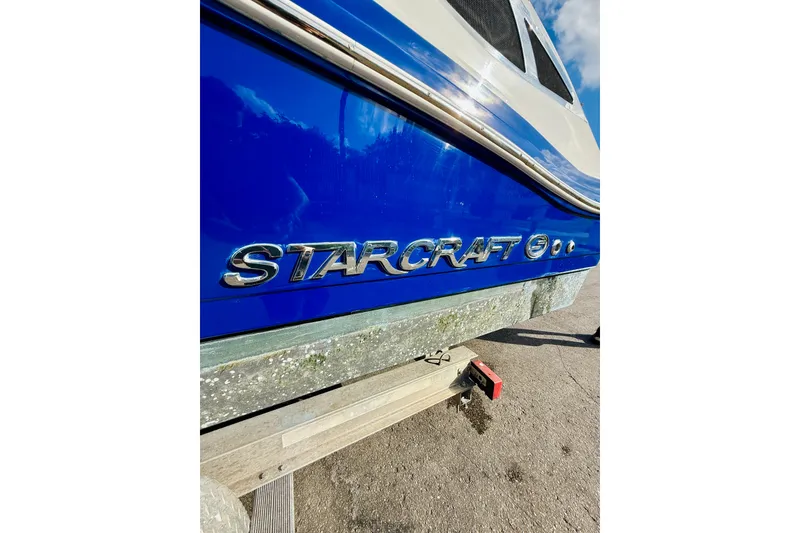 Slide: The Image of 2015 Starcraft Crossover 250 SCX OB boat with blue and white exterior detailing. - 9