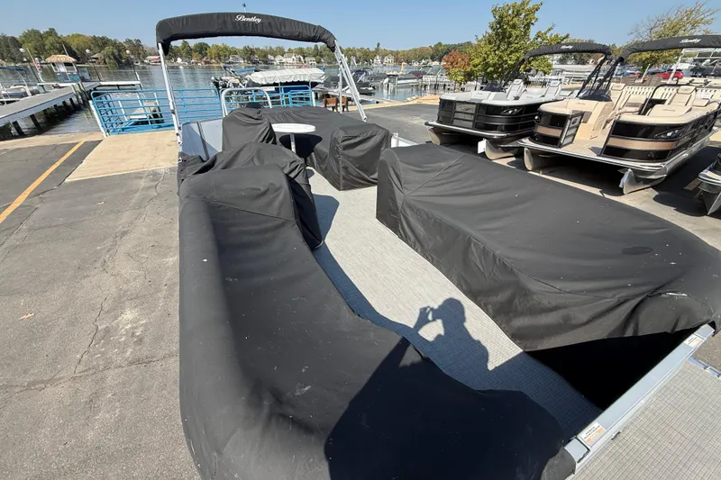 Slide: The Image of 2022 Bentley Pontoons 240 CRUISE covered at a marina, with other boats nearby. - 22
