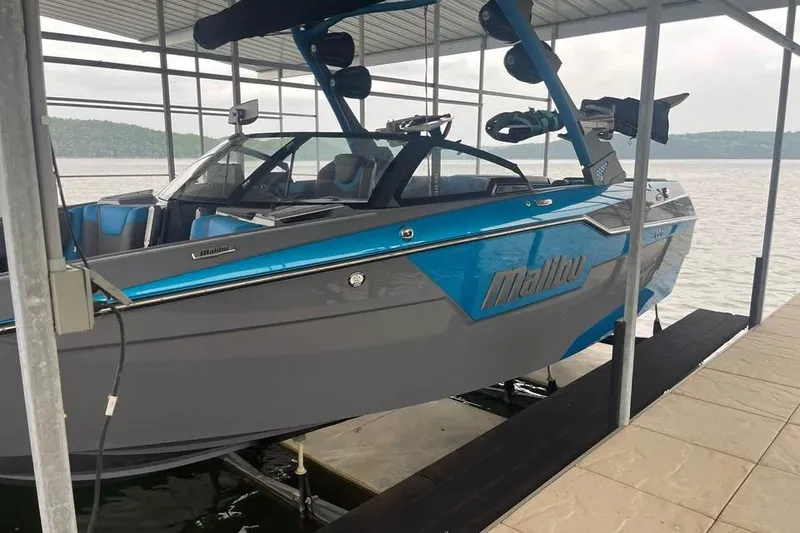 Slide: The Image of 2022 Malibu M220 boat docked under a covered structure by a lake. - 5