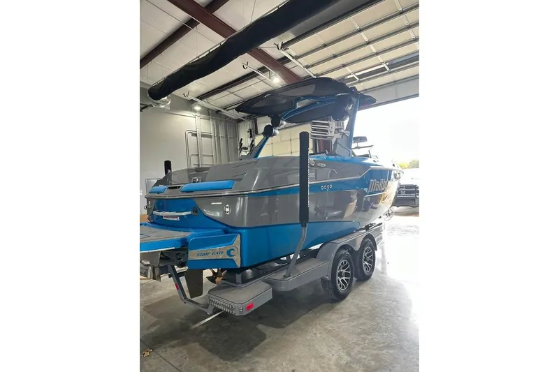 Slide: The Image of 2022 Malibu M220 boat in a garage, blue and gray exterior, on a trailer. - 6