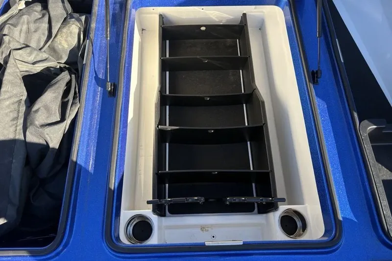 Slide: The Image of 2021 Caymas CX20 boat storage compartment with black dividers and blue trim. - 7