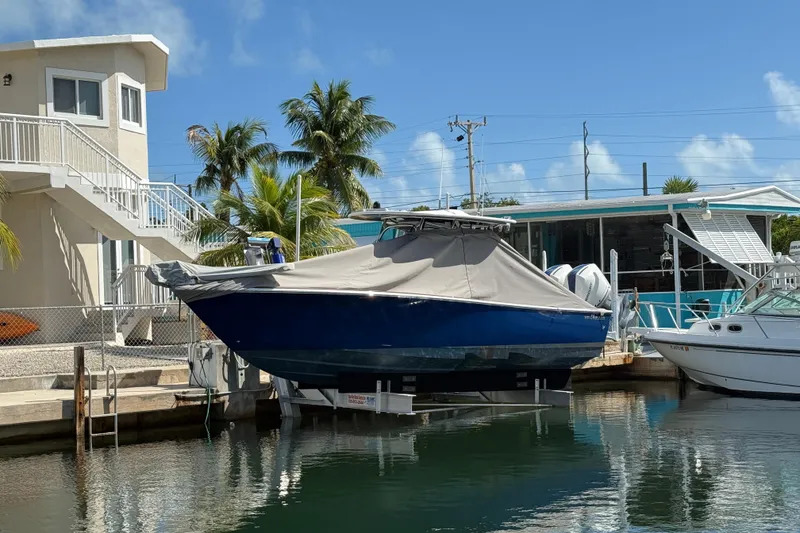 The Image of 2024 Valhalla Boatworks V-29 Hybrid covered, docked near waterfront homes and palm trees. - 0
