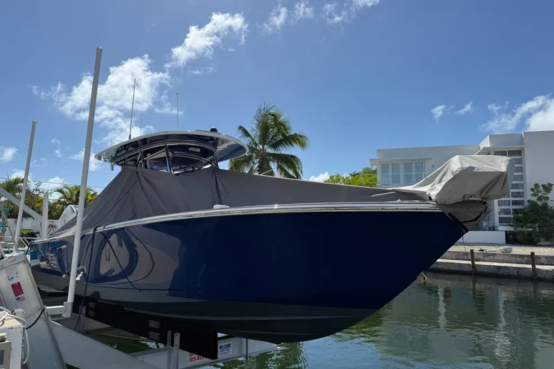 Slide: The Image of 2024 Valhalla Boatworks V-29 Hybrid docked, covered, with palm trees and modern building in background. - 3