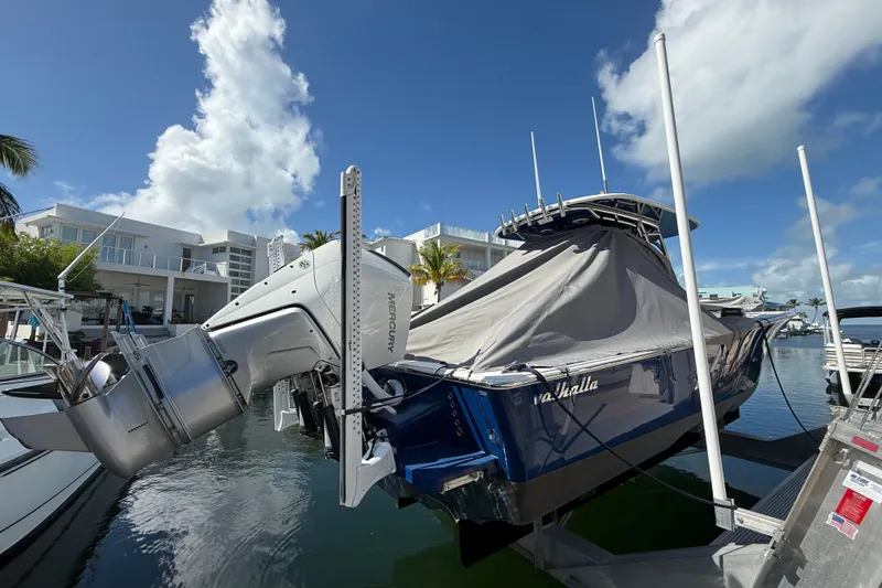 Slide: The Image of 2024 Valhalla Boatworks V-29 Hybrid docked, covered, with Mercury outboard engine, under clear sky. - 4