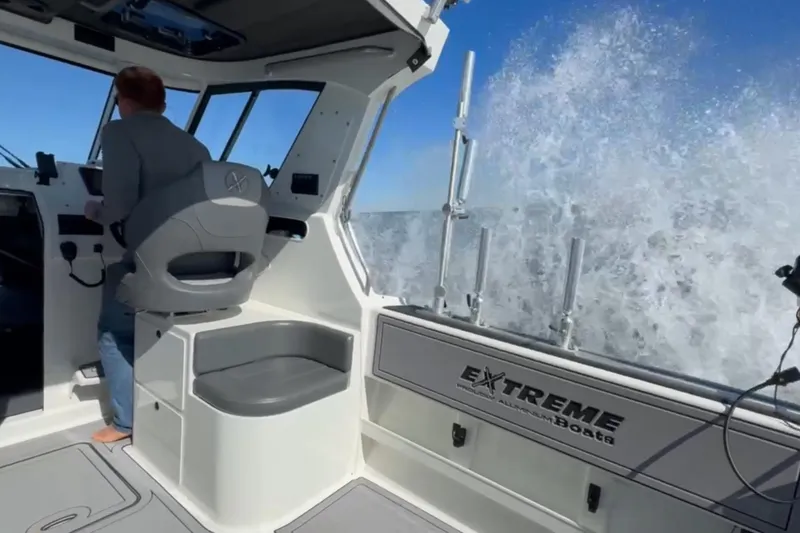 Slide: The Image of 2023 Extreme Boats 695 Game King navigating waves, interior view with helm and seating. - 12