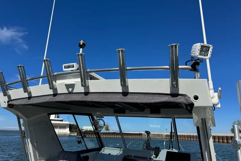 Slide: The Image of 2023 Extreme Boats 695 Game King, featuring rod holders and navigation equipment against a clear blue sky. - 22