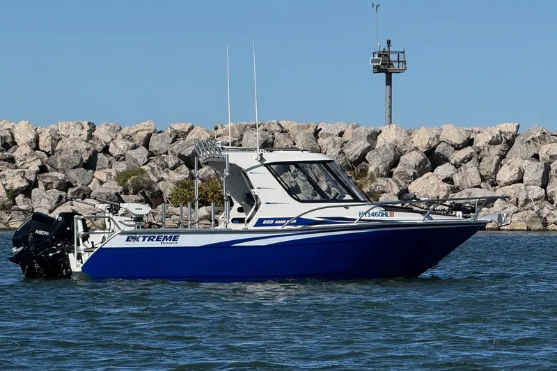 Slide: The Image of 2023 Extreme Boats 695 Game King in water near rocky shoreline. - 3