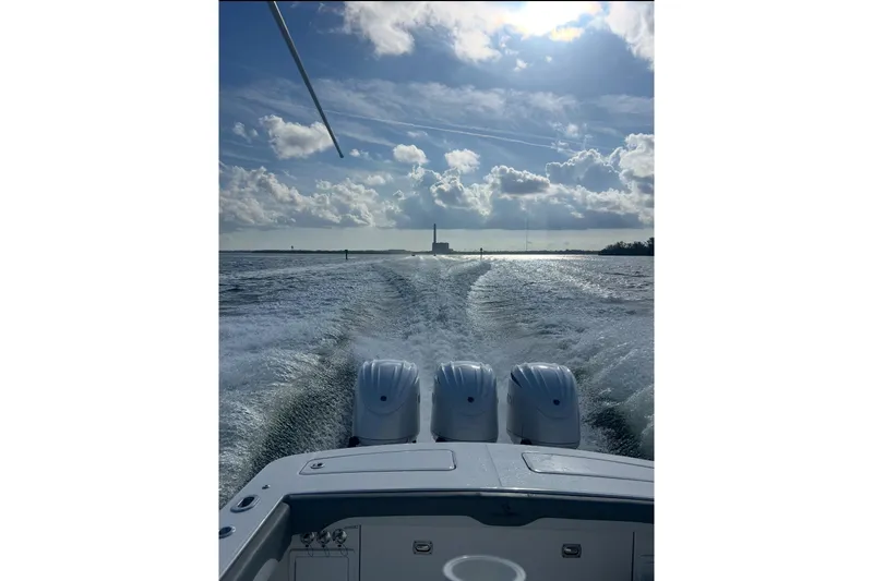 Slide: The Image of 2024 Regulator 34 c boat cruising on open water under a partly cloudy sky. - 7