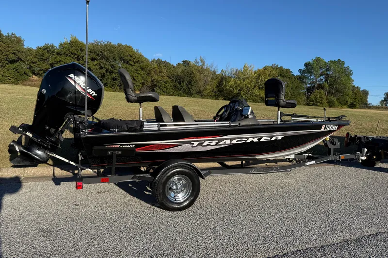 Slide: The Image of 2020 Tracker Pro Team 175 boat on trailer, parked on road, with Mercury outboard motor. - 2