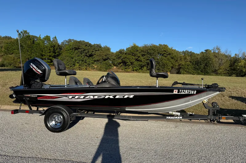 Slide: The Image of 2020 Tracker Pro Team 175 boat on trailer, parked on roadside with trees in background. - 21