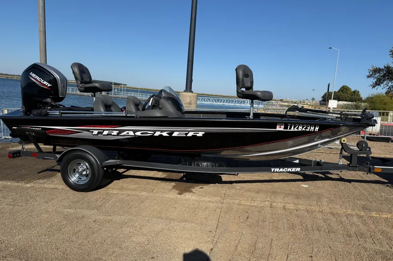Slide: The Image of 2020 Tracker Pro Team 175 boat on trailer by waterfront, featuring Mercury engine. - 40