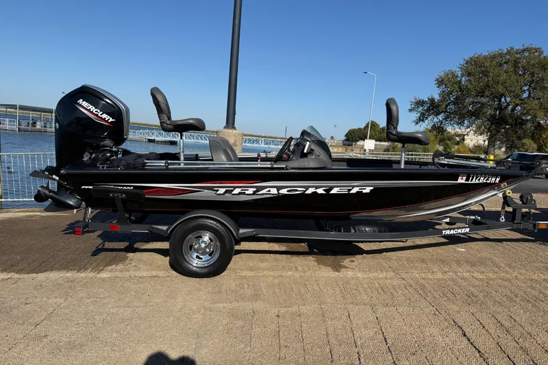 Slide: The Image of 2020 Tracker Pro Team 175 boat on trailer by waterfront, featuring Mercury engine. - 41
