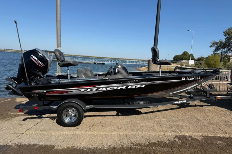 Slide: The Image of 2020 Tracker Pro Team 175 boat on trailer by the water, featuring Mercury engine. - 44
