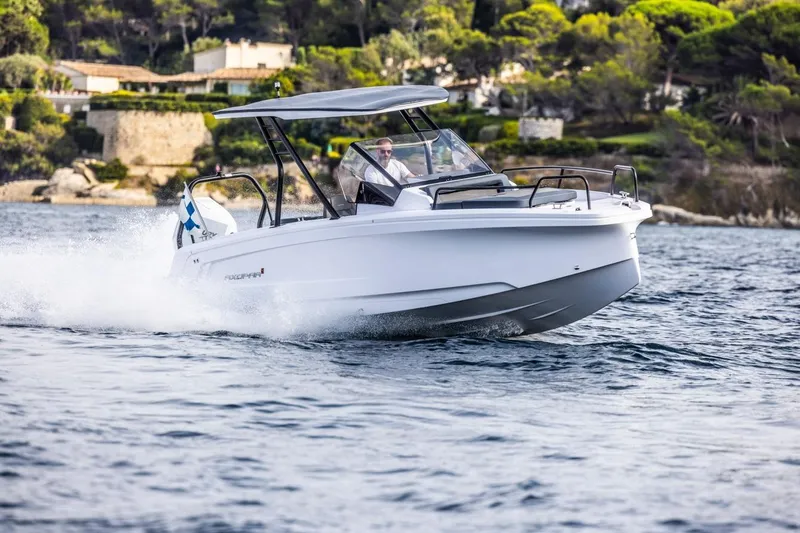The Image of 2025 Axopar 25 Cross Top boat cruising on water near scenic coastline. - 0