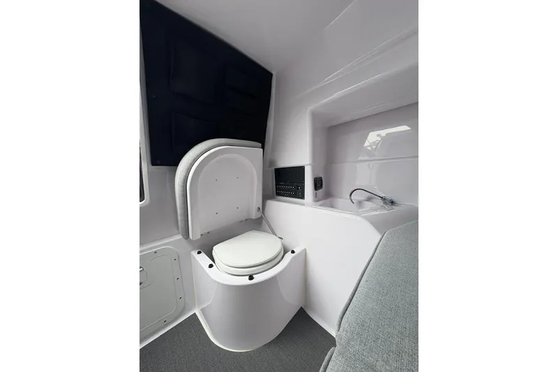 Slide: The Image of 2025 Axopar 25 Cross Top interior with compact marine toilet and sink. - 8