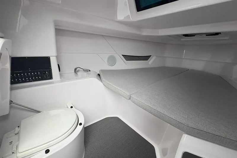 Slide: The Image of 2025 Axopar 25 Cross Top cabin interior with toilet and cushioned seating. - 9
