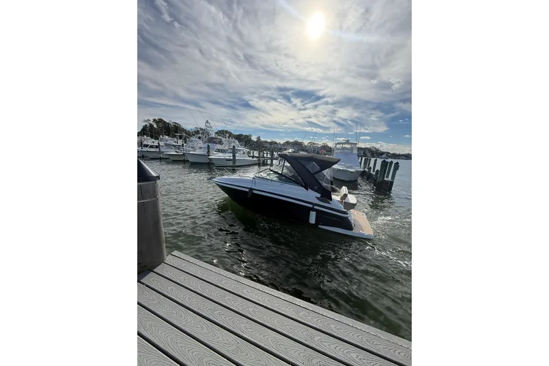 Slide: The Image of 2017 Regal 28 Express boat cruising on a calm lake under a partly cloudy sky. - 2