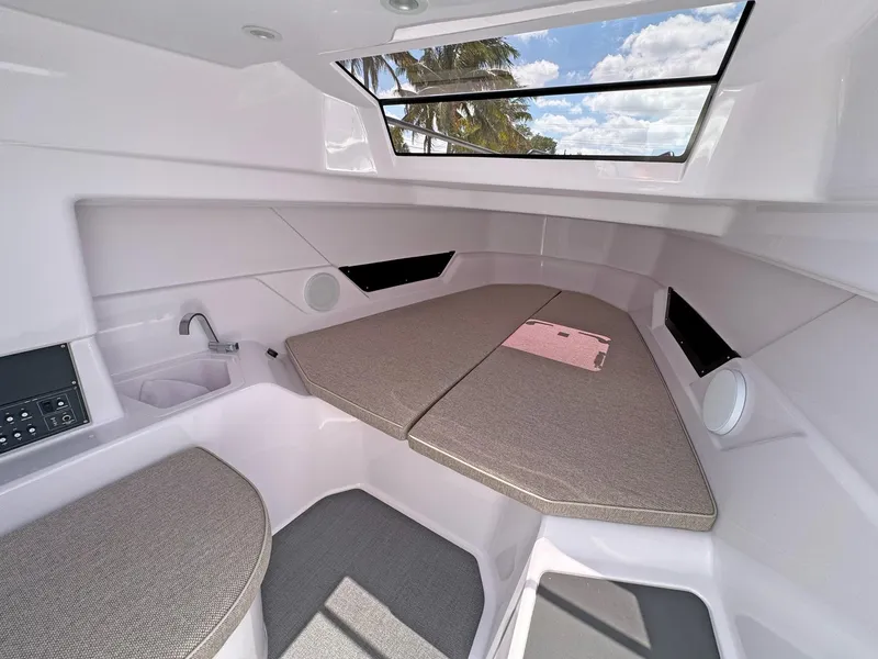 Slide: The Image of 2024 Axopar 25 Cross Top cabin interior with seating and window view. - 9