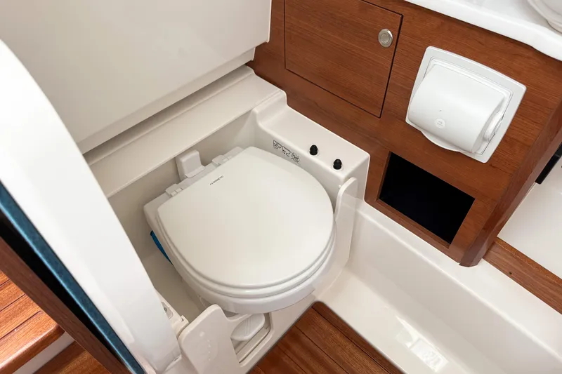Slide: The Image of 2026 Pursuit S 328 Sport boat bathroom with wooden accents and compact toilet. - 22