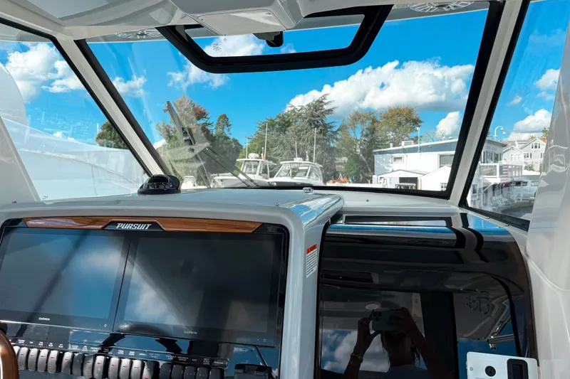 Slide: The Image of Interior view of 2026 Pursuit S 328 Sport boat cockpit with dual screens and clear sky. - 24