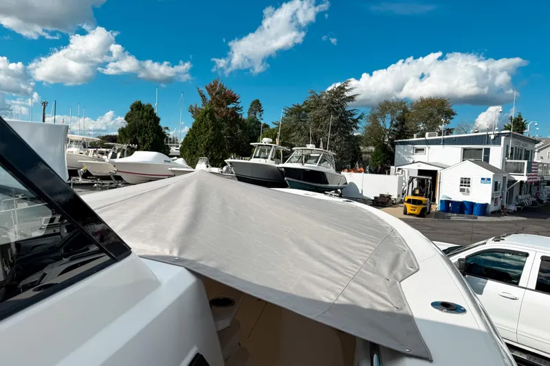 Slide: The Image of 2026 Pursuit S 328 Sport boat in marina, covered deck, clear sky, surrounding boats. - 26