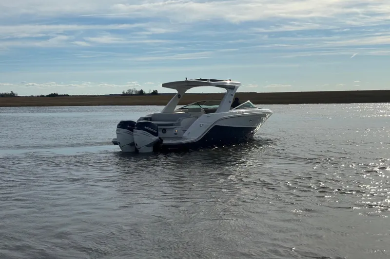 Slide: The Image of 2023 Sea Ray 310 SLX boat cruising on a calm waterway under a clear sky. - 29