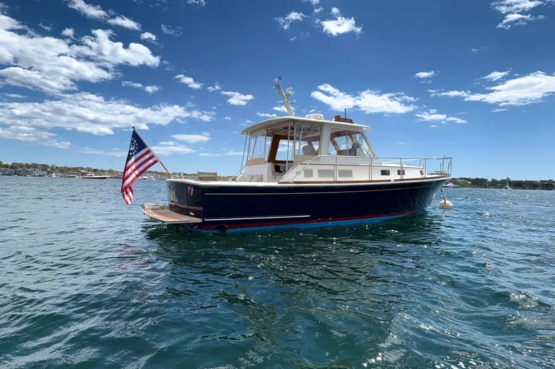 Slide: The Image of 1999 Grand Banks 38 Eastbay HX yacht on water, American flag, clear sky. - 25