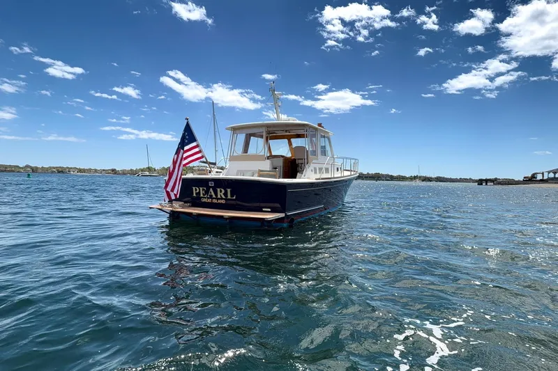 Slide: The Image of 1999 Grand Banks 38 Eastbay HX yacht named "Pearl" on open water under blue sky. - 26