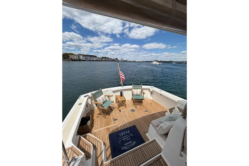 Slide: The Image of 1999 Grand Banks 38 Eastbay HX yacht deck with chairs, overlooking serene water and blue sky. - 28