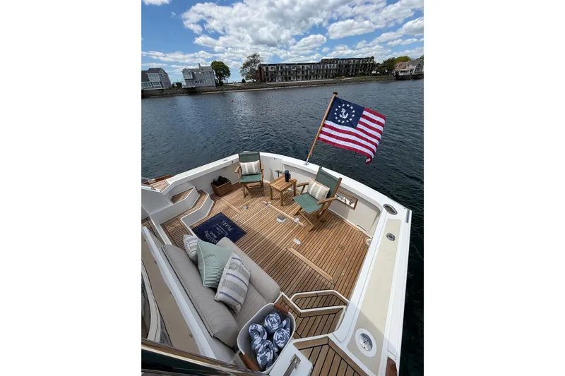 Slide: The Image of 1999 Grand Banks 38 Eastbay HX yacht deck with chairs, flag, and scenic waterfront view. - 29