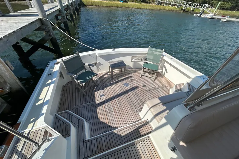 Slide: The Image of 1999 Eastbay 38 boat deck with chairs, table, and wooden flooring by the water. - 3