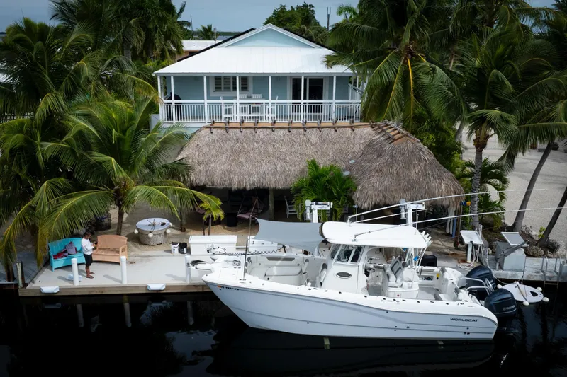 Slide: The Image of 2021 World Cat 295 CC boat docked by tropical house with palm trees. - 5