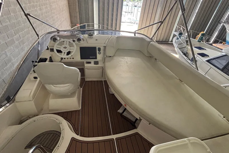 Slide: The Image of 2009 Azimut 43 yacht interior with helm, seating, and wooden flooring in a marina setting. - 6