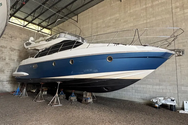Slide: The Image of 2009 Azimut 43 yacht in storage, blue and white hull, supported by stands. - 8