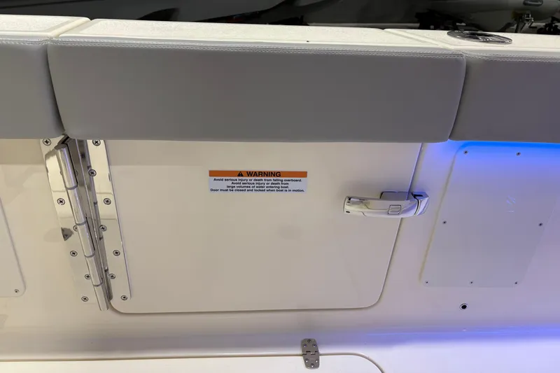 Slide: The Image of 2026 Scout 288 LXF boat door with warning label and secure handle. - 9