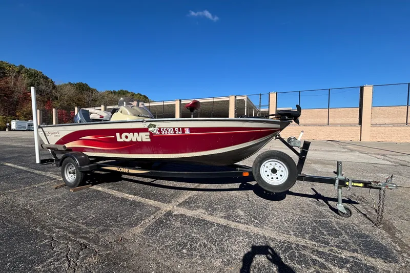 Slide: The Image of 2002 Sea Nymph FM 165 S boat on trailer, parked in a lot under clear blue sky. - 2
