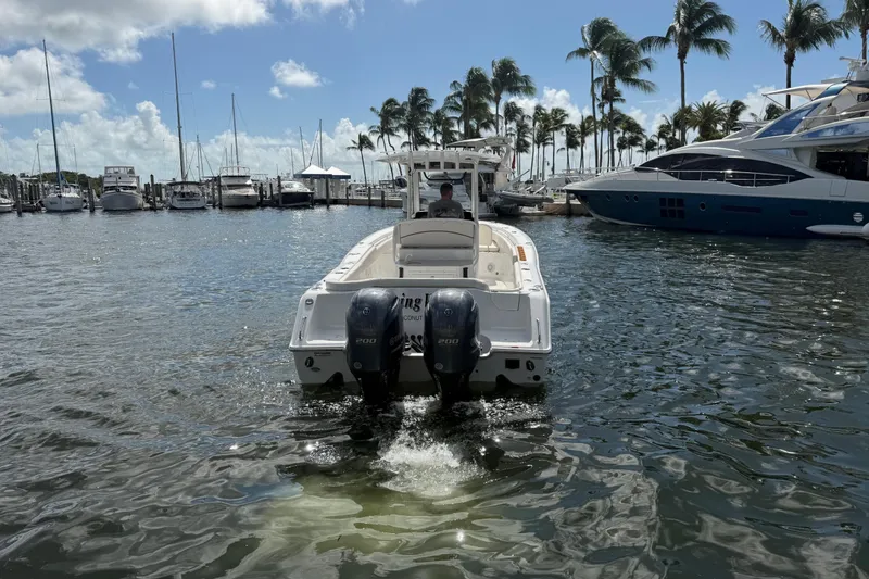 Slide: The Image of 2022 Sea Hunt Ultra 275 SE boat in marina, surrounded by palm trees and yachts. - 14
