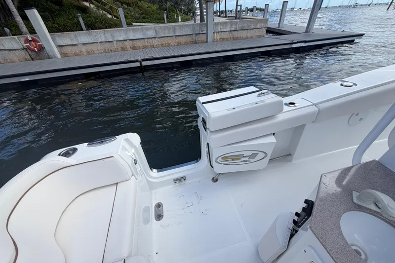 Slide: The Image of 2022 Sea Hunt Ultra 275 SE boat interior near dock, featuring seating and storage. - 23