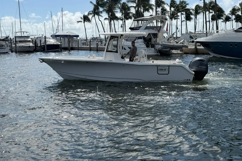 Slide: The Image of 2022 Sea Hunt Ultra 275 SE boat cruising in a marina with palm trees. - 6