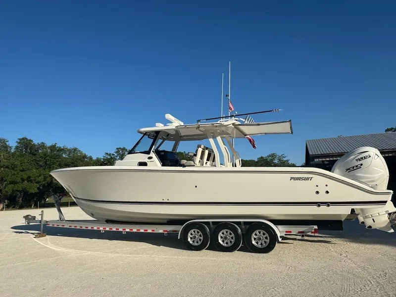 Slide: The Image of 2024 Pursuit S 358 Sport boat on trailer, parked outdoors under clear blue sky. - 17