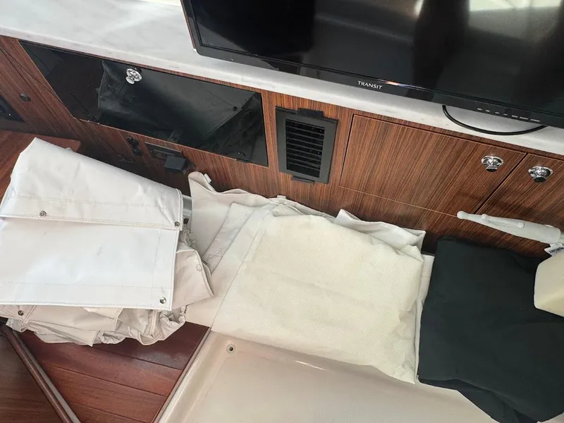Slide: The Image of Interior of 2024 Pursuit S 358 Sport boat with folded white covers and wooden paneling. - 36