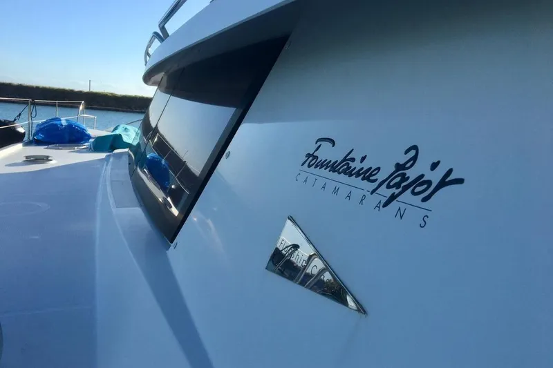 Slide: The Image of 2014 FONTAINE PAJOT 63 catamaran, sleek design, docked by the water. - 4